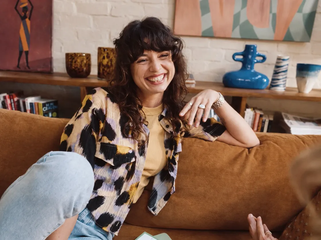A smiling creator sitting on a sofa in a colourful room