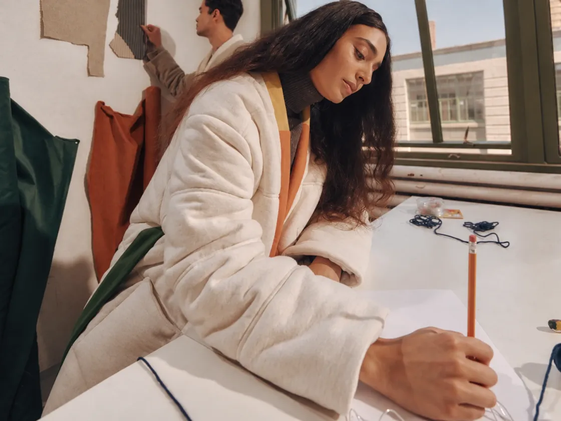 Someone sketching at a desk in a bright studio