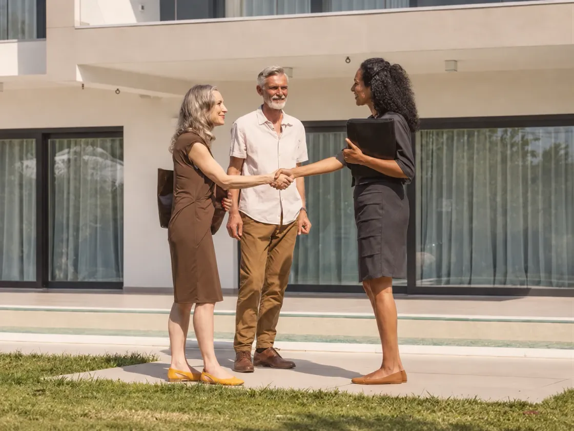 Three people meeting in front of a house