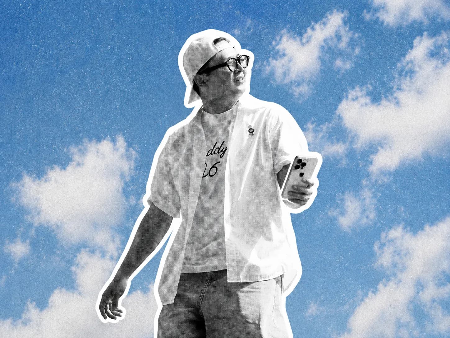 A stylish young creator standing confidently against a blue sky, holding a phone