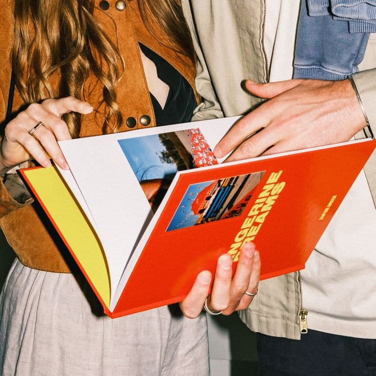 Une personne feuilletant un livre imprimé à la couverture rouge
