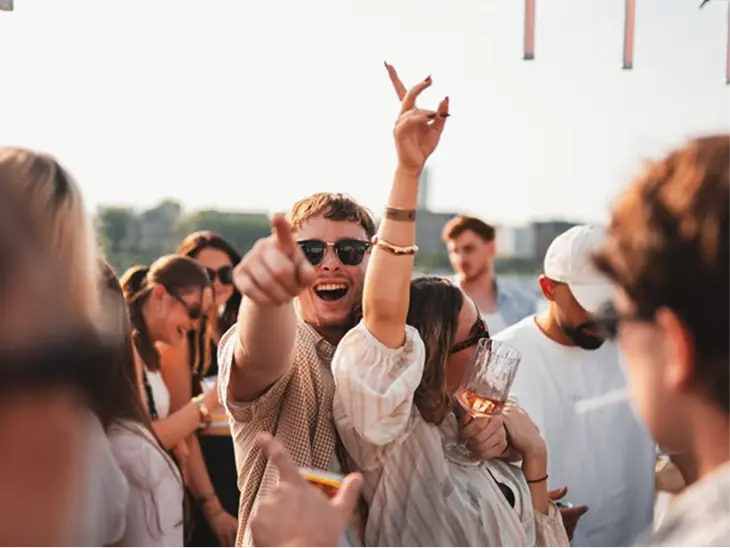 Friends dancing and cheering at a rooftop party