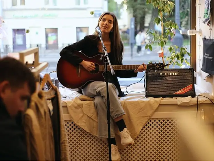 A singer playing acoustic guitar at an intimate gig