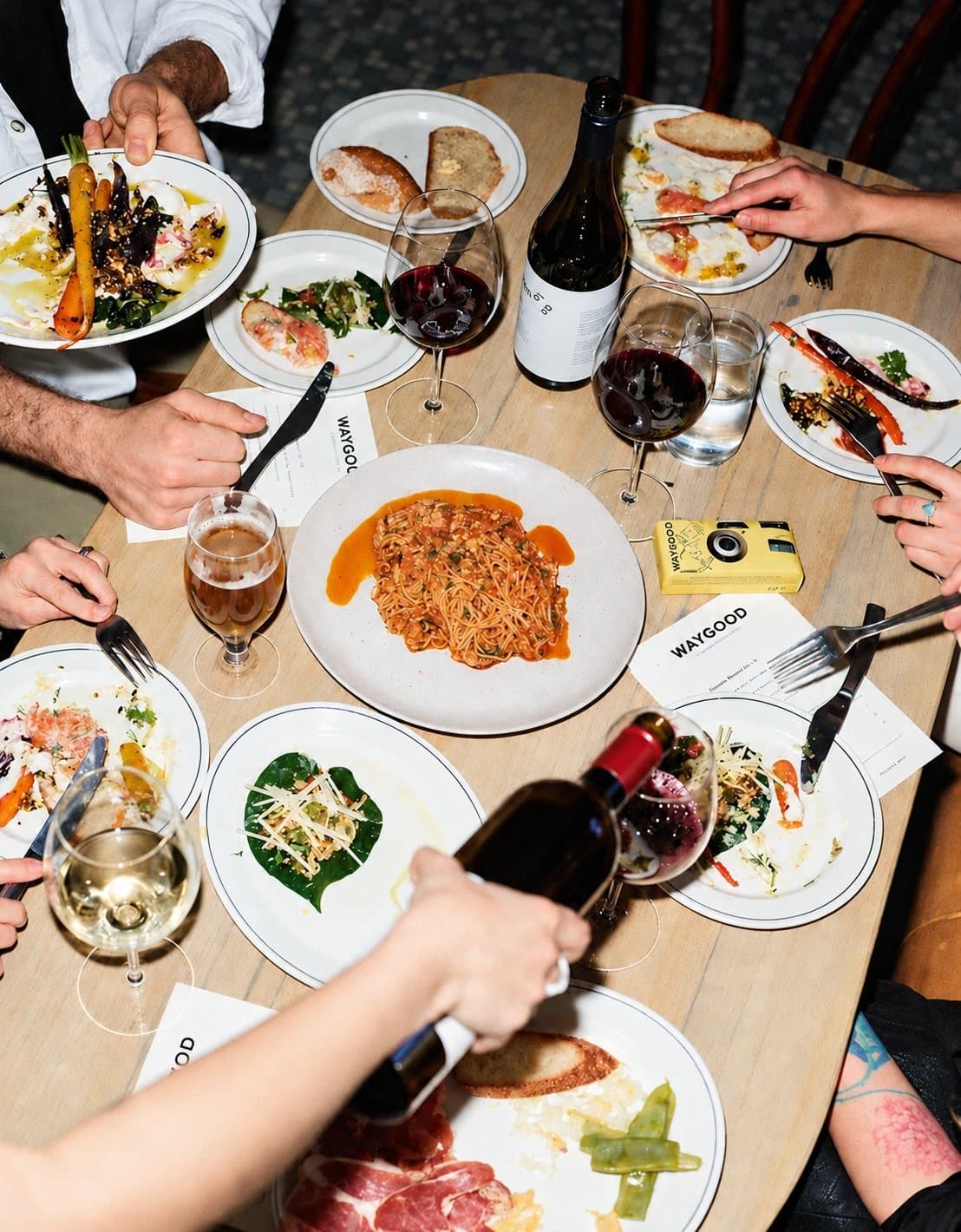 Friends sharing plates, pasta and wine around a restaurant table