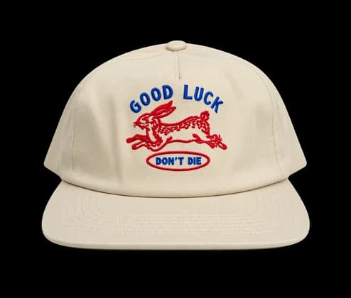 Une casquette crème brodée d'un motif « Good luck »